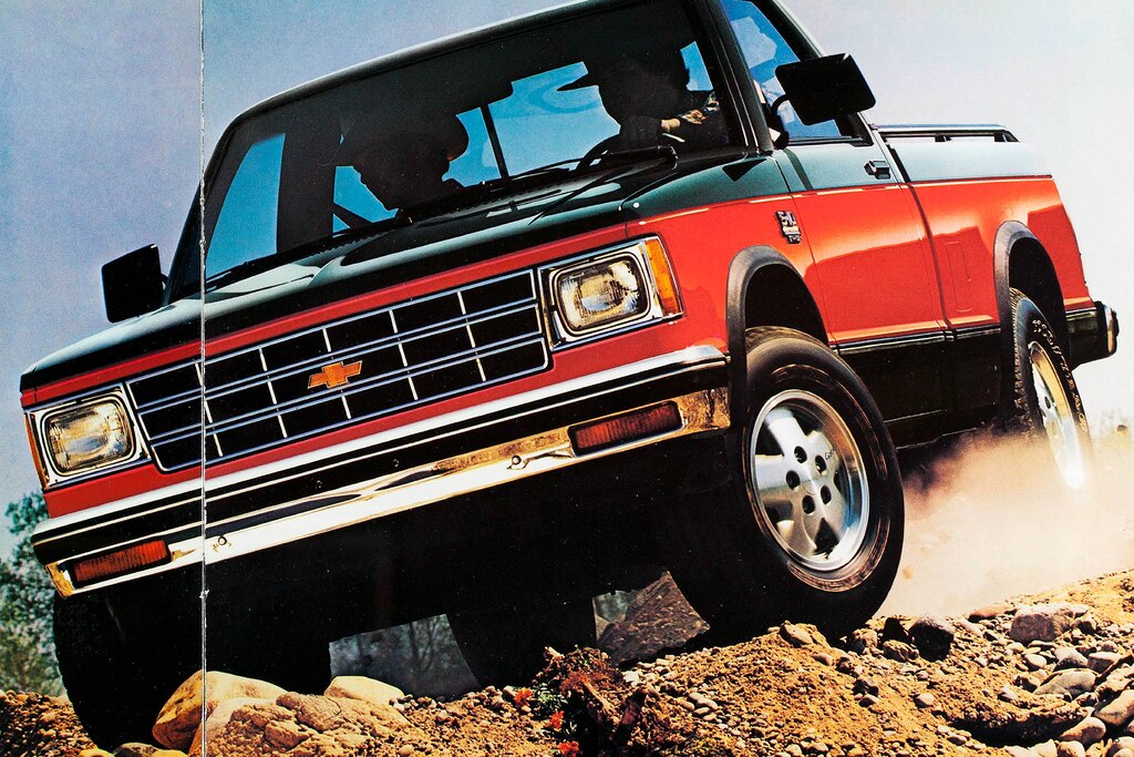 Una pickup Chevy S-10 de 1983 a dos tonos en rojo y negro transita un terreno accidentado en una foto del folleto de 1983.