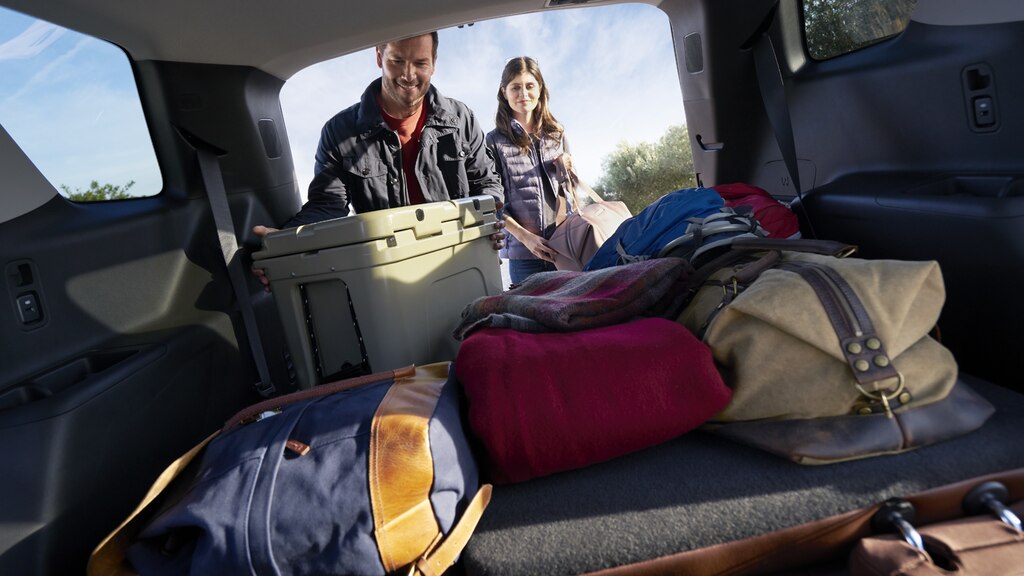Un hombre y una mujer descargando equipos de camping desde la parte trasera de una Traverse.