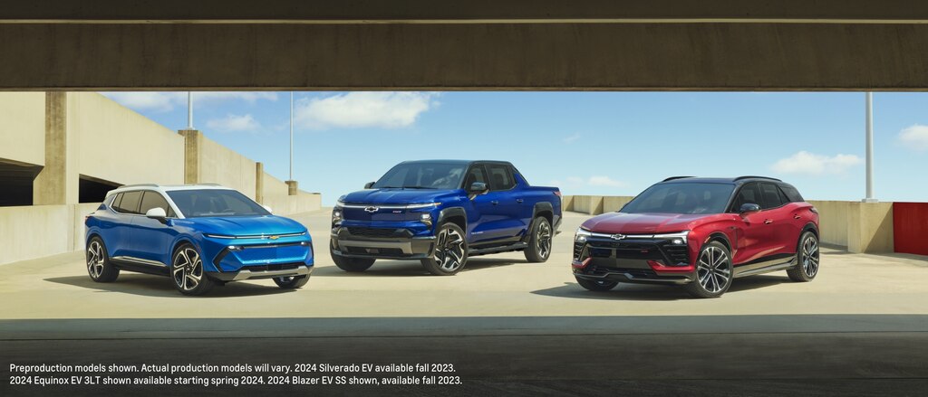 Una Equinox EV azul, una Silverado EV azul y una Blazer EV roja estacionadas juntas en el nivel superior abierto de un estacionamiento.