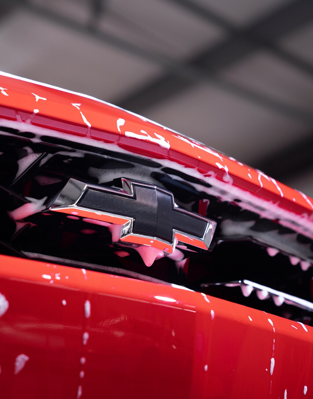 Primera plano en detalle de la parrilla frontal de un Chevy Camaro rociado con gotas de espuma blanca.