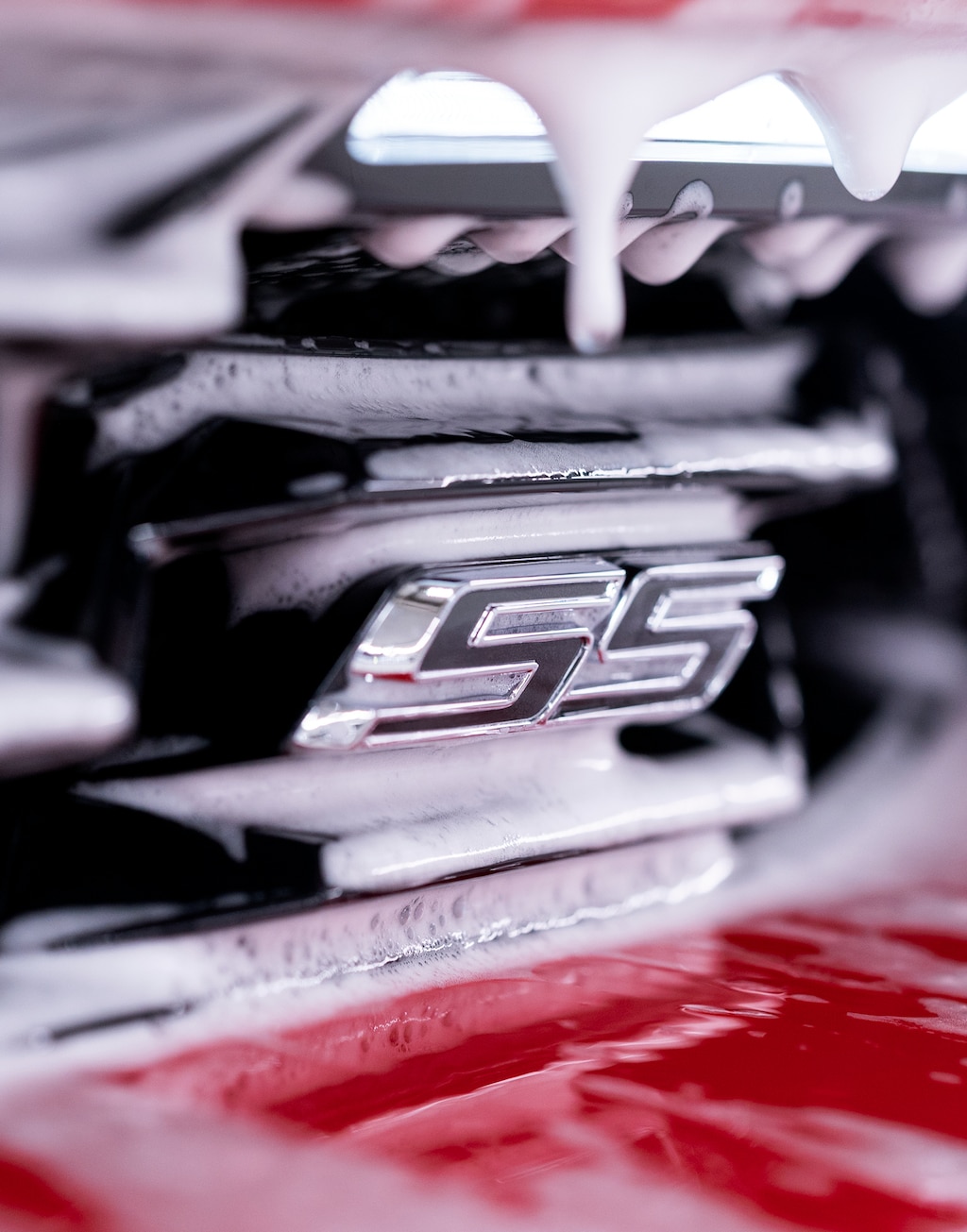 Primer plano en detalle del emblema del SS en un Chevy Camaro con espuma blanca en las ranuras que lo rodean.