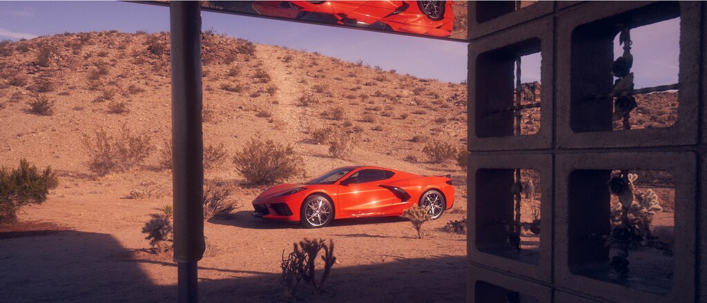 Un Corvette 2020 en Rojo Antorcha en un paisaje desértico, visto a través de una ventana.