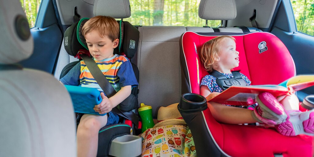 Dos niños en sillitas en los asientos traseros de un Bolt EV. Uno está usando una tablet y el otro tiene un libro en la mano y mira por la ventana.