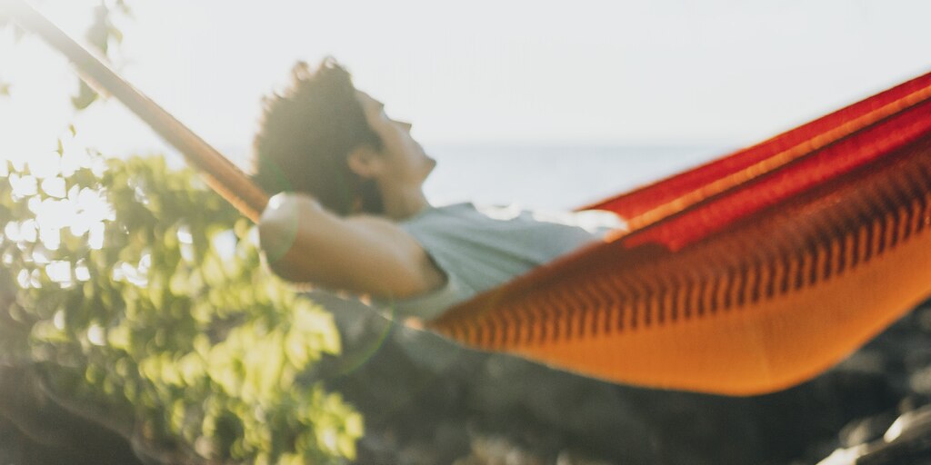 Un hombre relajándose en una hamaca roja y naranja.