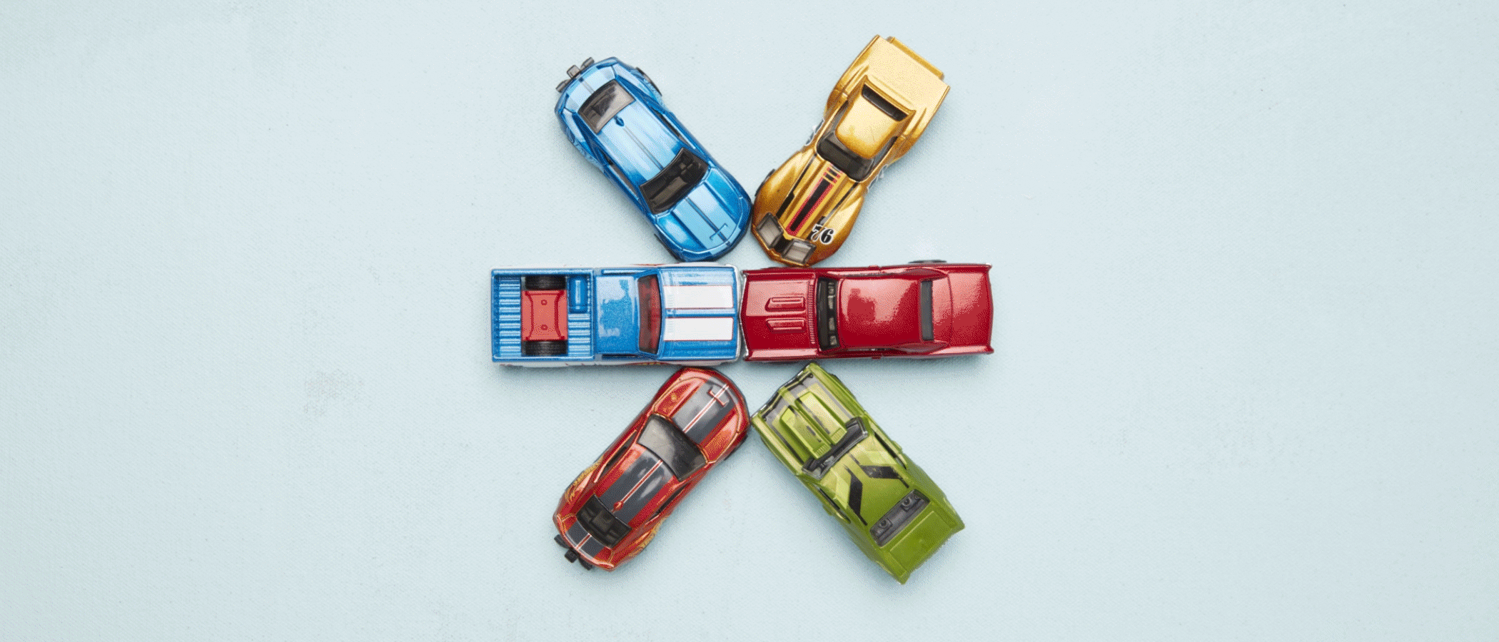 Una animación gif de seis autos Hot Wheels vistos desde arriba mientras se mueven en círculo y luego se unen en el centro.