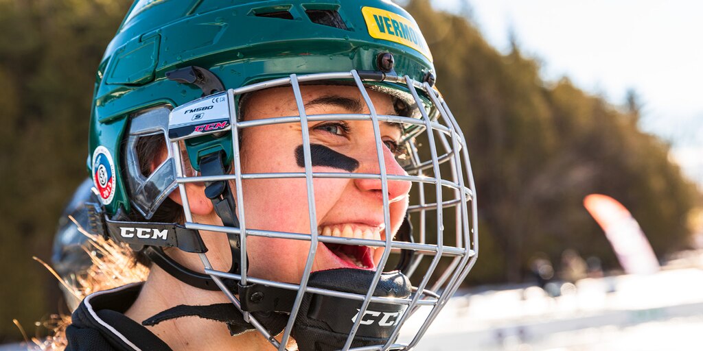 Primer plano de una mujer con un casco de hockey y protección facial.