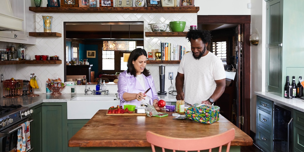 Beth Morgan y un hombre de pie juntos cortando alimentos en una mesa de cocina.