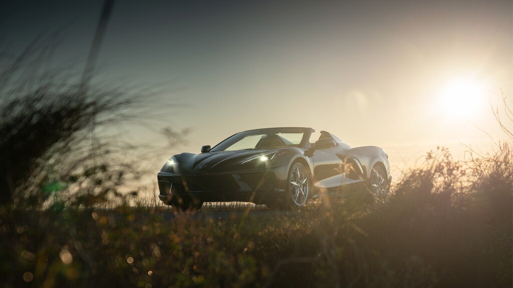 Silueta de un Corvette Convertible 2020 en Bronce Zeus Metálico en contraste con el sol poniente en un camino de la costa en Carolina del Sur.
