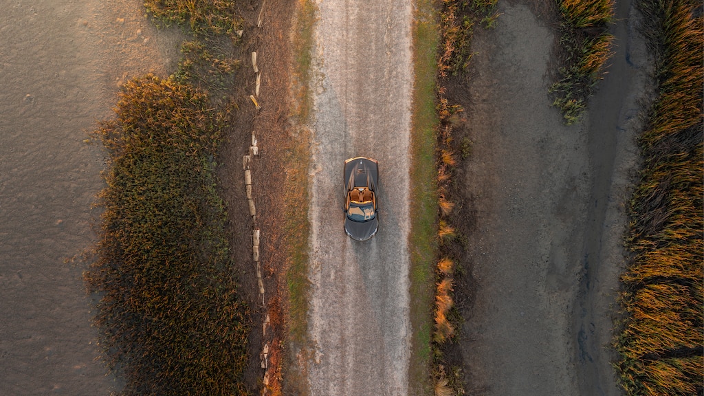 Foto de un Corvette Convertible 2020 en Bronce Zeus Metálico sacada con un dron desde arriba en un camino de la costa en Carolina del Sur.