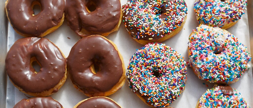 Una bandeja de donas cubiertas con glaseado de chocolate y chispas.