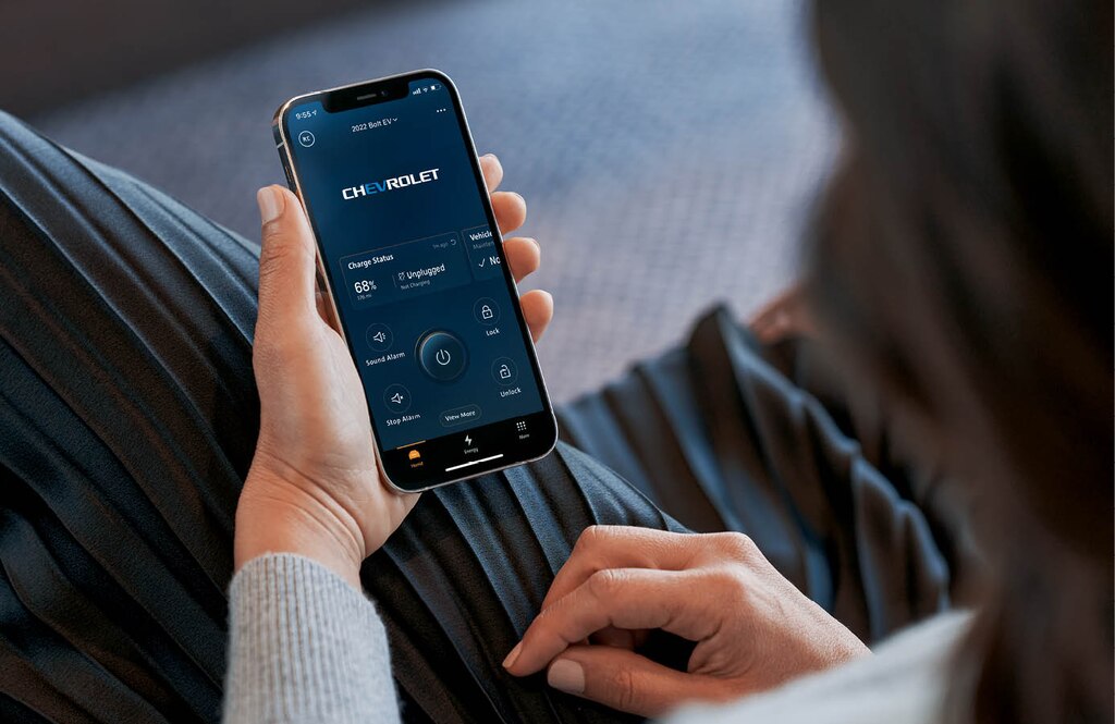 Una persona sostiene un smartphone en el que se muestra una de las pantallas de la función Energy Assist en la aplicación móvil myChevrolet.