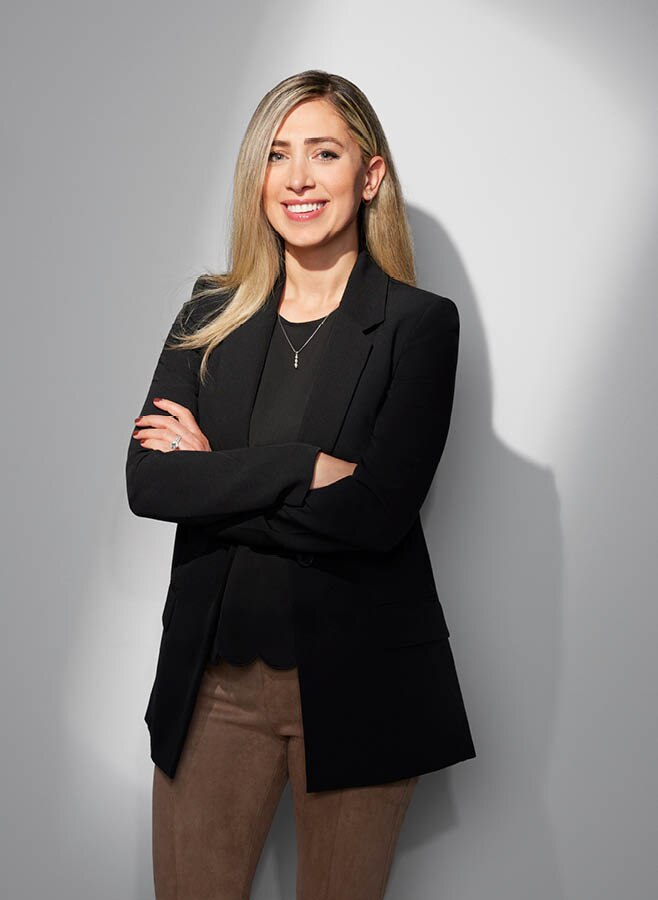 Dalya Aboona, líder de infraestructura y carga de vehículos eléctricos de General Motors, está parada con los brazos cruzados mientras sonríe a la cámara.