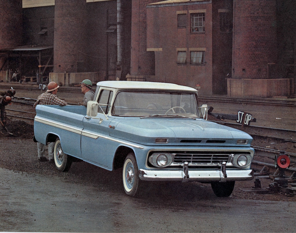 Una fotografía vieja del folleto de la camioneta serie C/K 1962 mostrando una pickup azul claro de la serie C/K con dos hombres de pie detrás de la caja.