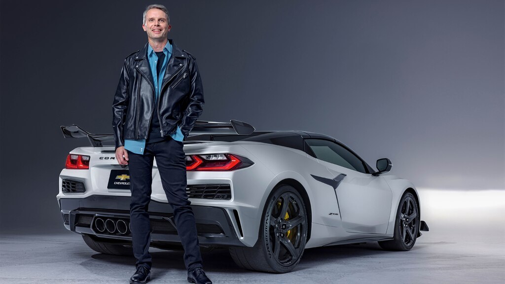 Alex MacDonald sonríe a la cámara mientras se coloca en la parte trasera de un Corvette Z06 Blanco.