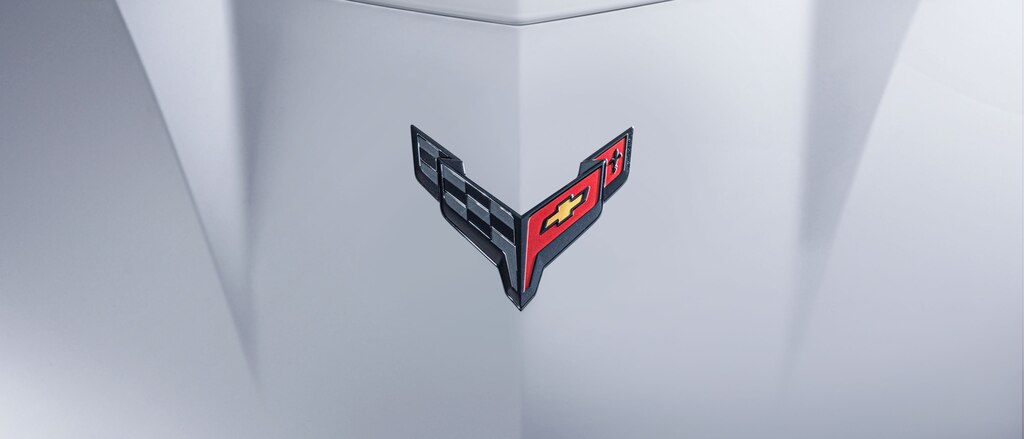 Un primer plano del emblema de banderas cruzadas del Corvette en el cofre de un Corvette Z06 Blanco.