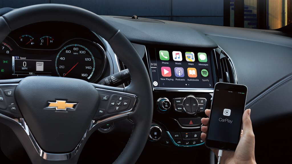 Una mano sosteniendo un teléfono con la interfaz Apple CarPlay abierta.