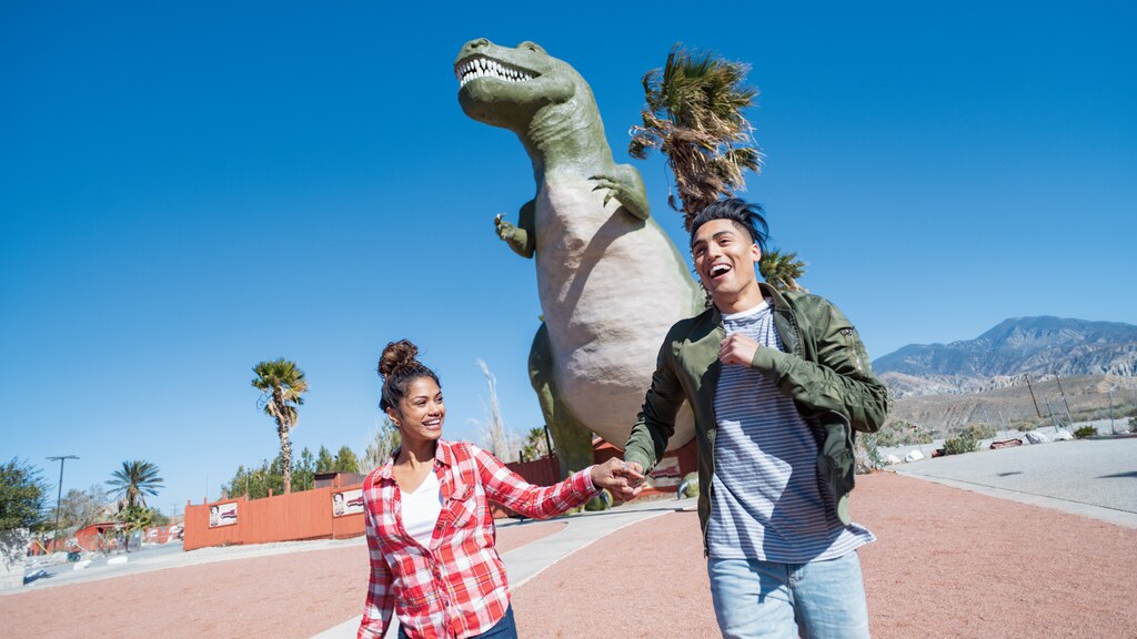 Una pareja tomada de las manos frente a uno de los Cabazon Dinosaurs.