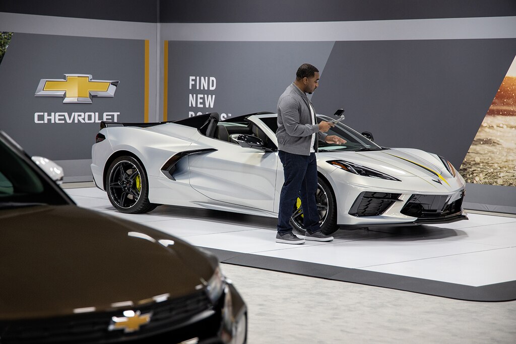 Un especialista en productos utilizando un dispositivo móvil para hacer una demostración de un Corvette 2022.