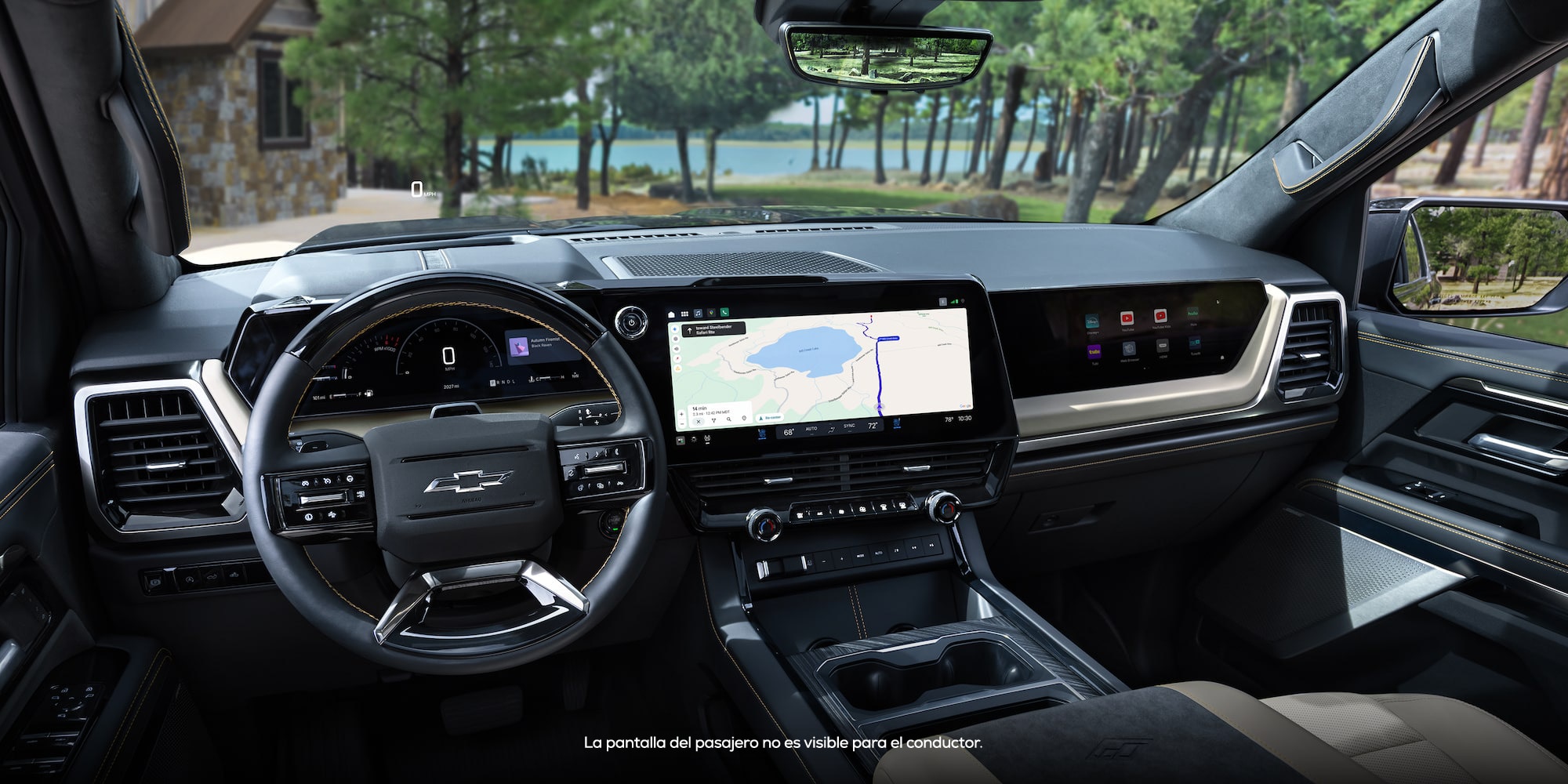 Vista desde el asiento del conductor del interior de la cabina delantera y el tablero de instrumentos de Chevy Silverado 1500 2027, con vista a un lago rodeado de árboles