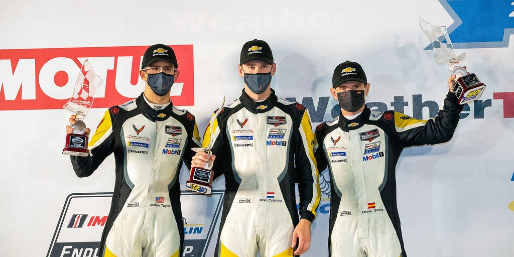 Pilotos del auto de carreras Chevy IMSA Corvette con trofeos
