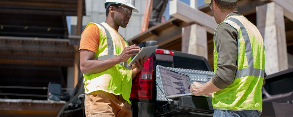 Dos trabajadores comerciales hablando cerca de una Chevy Silverado