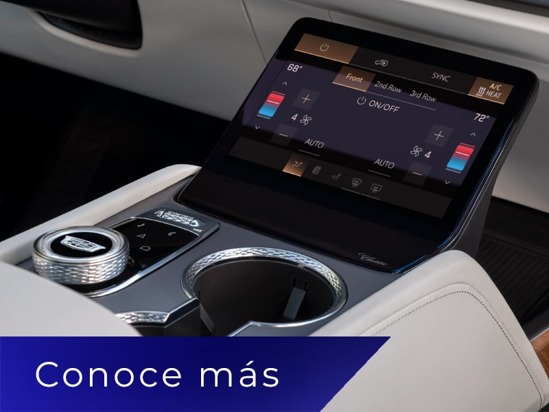 Primer plano de la consola central de una Cadillac VISTIQ con portavasos y una pantalla de control de climatización