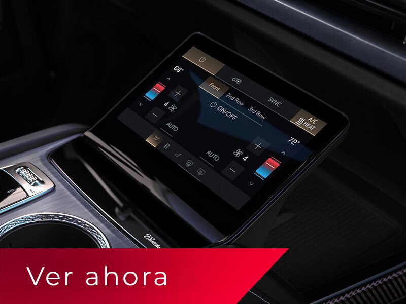 Primer plano de la consola central de una Cadillac VISTIQ 2027, que incluye los portavasos, la perilla de cambios y la pantalla de control de climatización