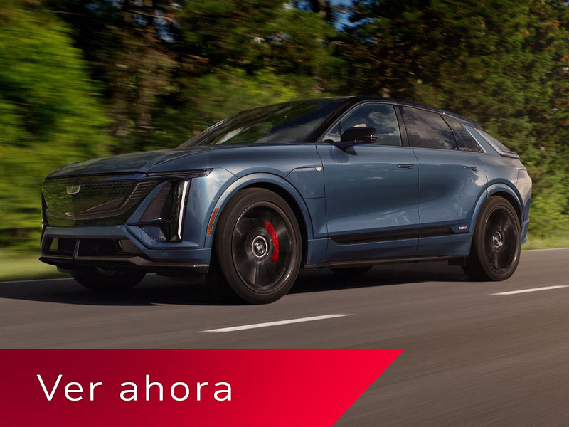 Vista de medio perfil baja de una Cadillac LYRIQ-V circulando por un camino con una hilera de árboles