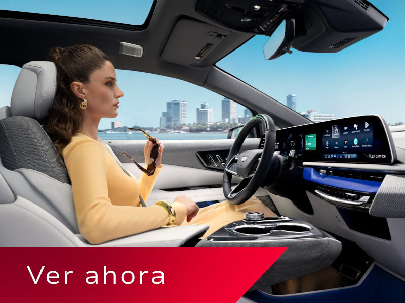 Vista del pasajero de una mujer conduciendo una Cadillac OPTIQ por la ciudad, usando la tecnología manos libres Super Cruise